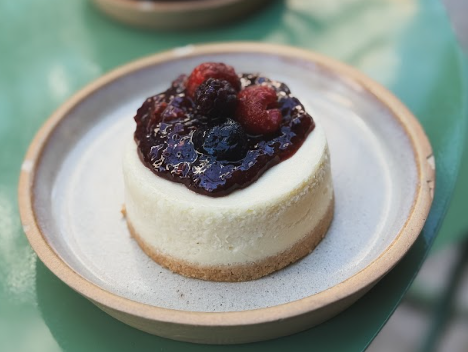 Cheesecake con salsa y frutos rojos en plato de cerámica