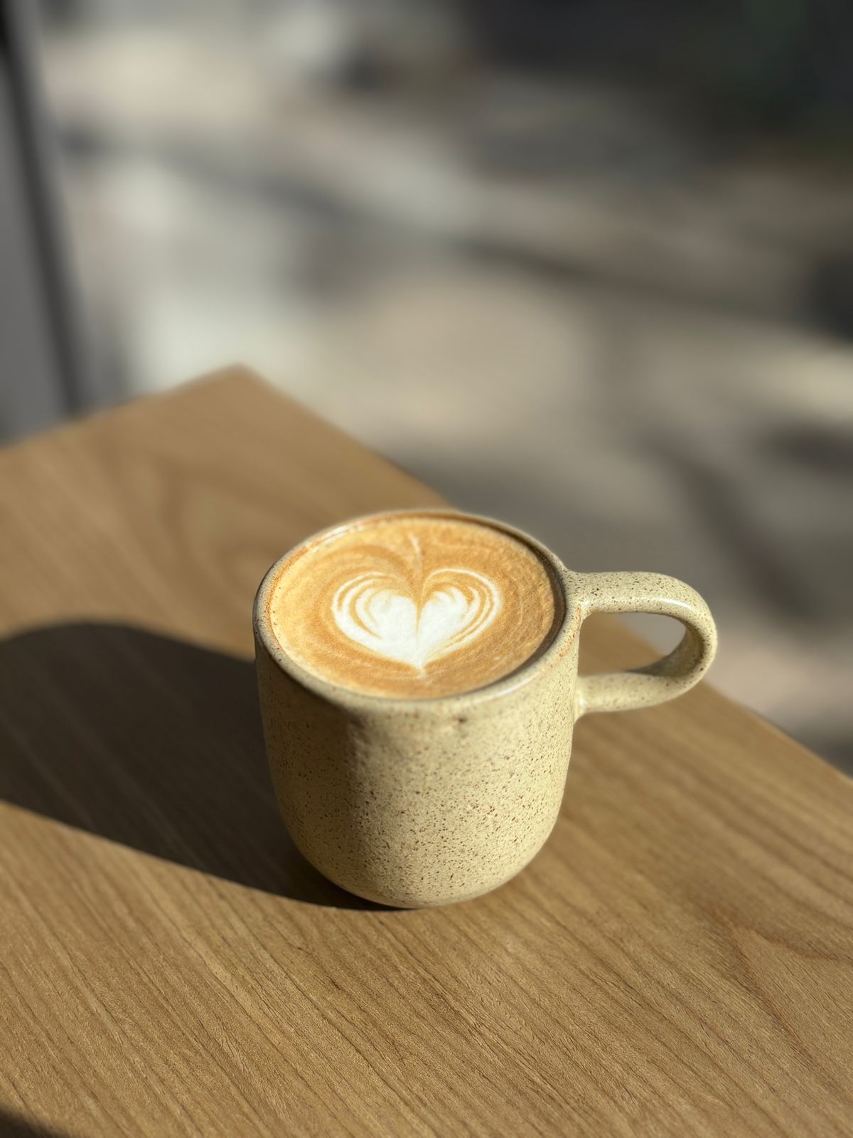 Flat white con corazón de latte art bajo el sol