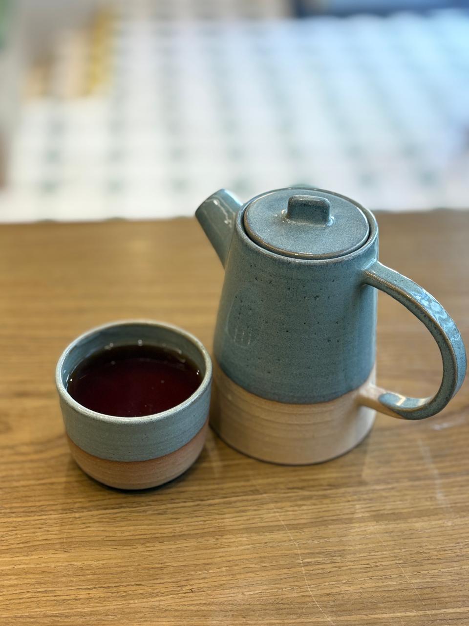 Tetera de cerámica celeste junto a una taza de té